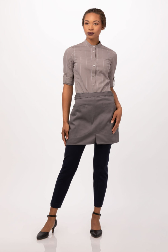A grey half bistro apron worn over a button-up shirt, modelled with dark pants and heels. The apron has a logo.