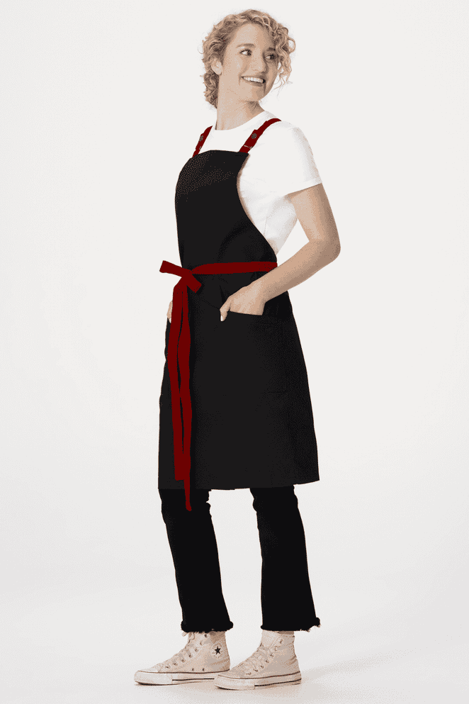 A black apron with a red belt and pockets, worn over a white t-shirt and black trousers. It features a logo.