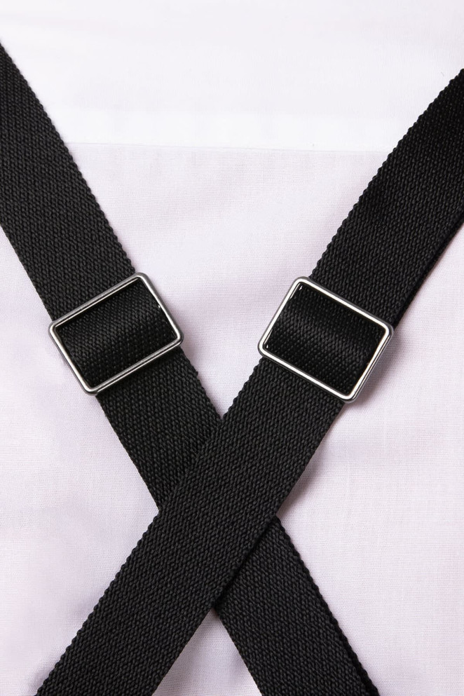 A close-up of black adjustable straps crossing over a white apron. The straps have silver hardware.