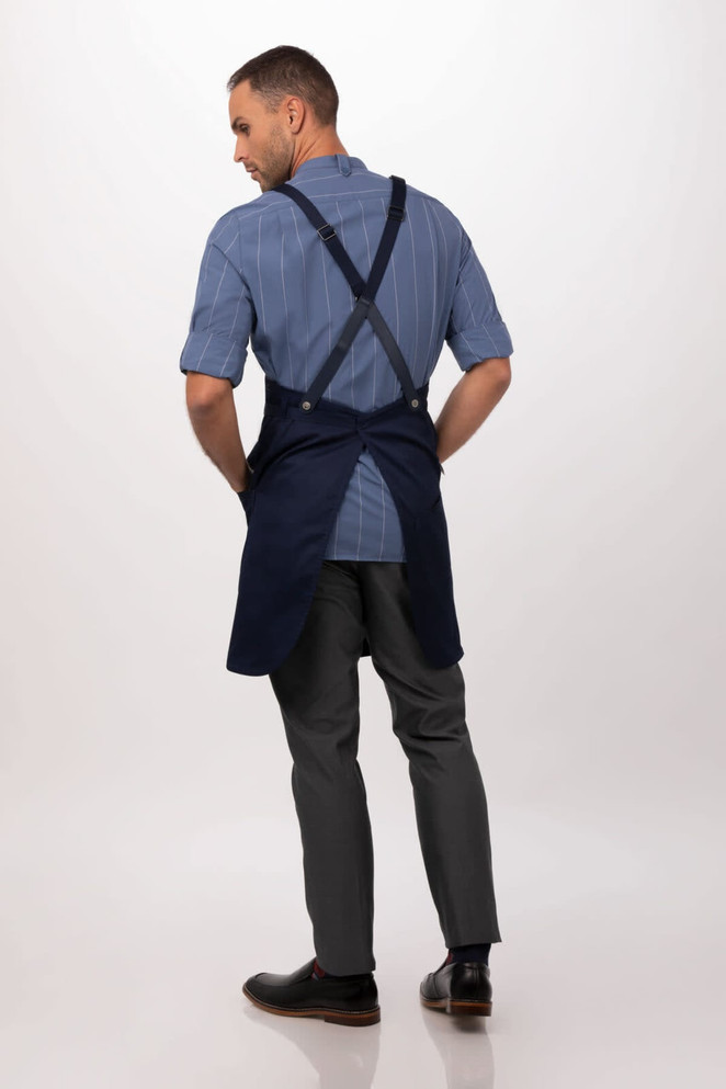 A navy Largo Bib Apron worn by a model, featuring cross-back straps and a simple design, with a logo on the apron.
