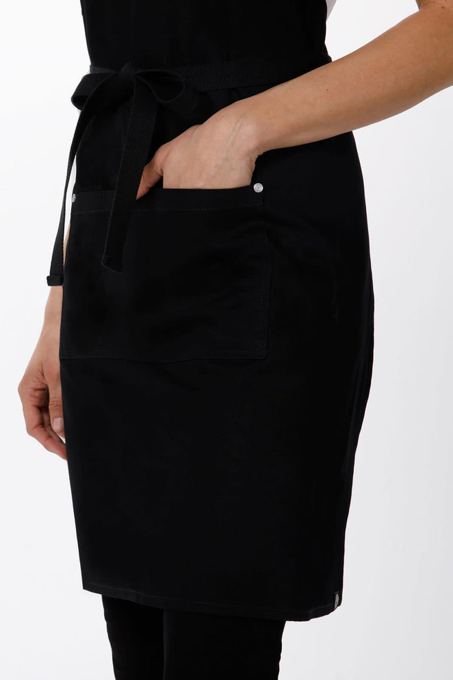 A black cross-back apron with a front pocket and adjustable tie, featuring a simple design and overall sleek appearance.