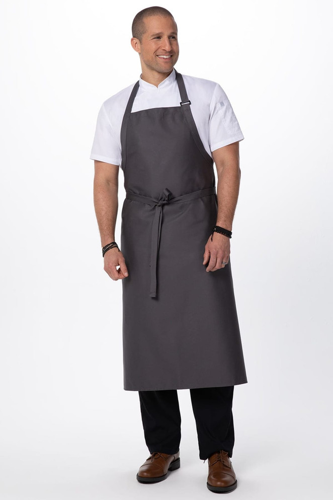A grey large bib apron worn by a smiling man, featuring an adjustable neck strap and waist ties.
