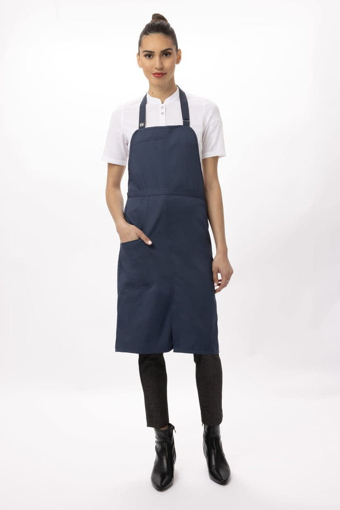 A navy blue bib apron featuring a front pocket, worn by a model with a high bun and white shirt.