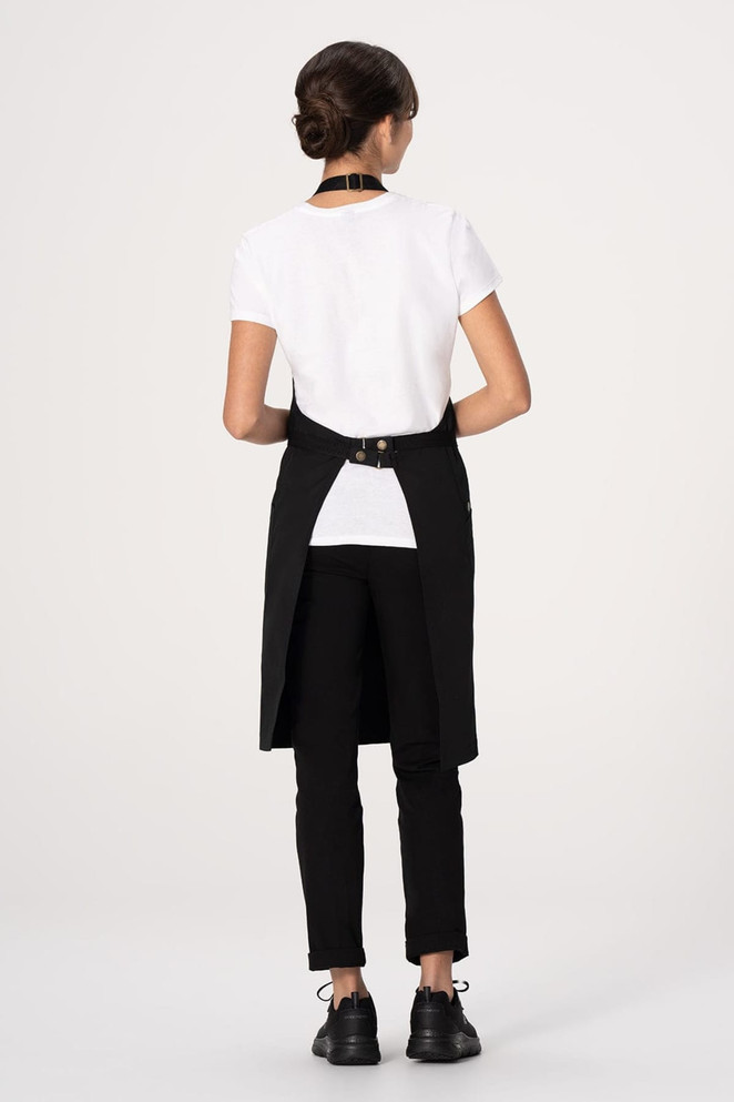 A black bib apron with a unique back design, worn over a white shirt and black pants, featuring a logo.
