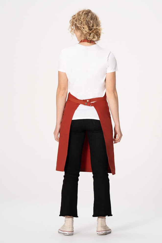 A red bib apron worn by a person from the back, paired with a white t-shirt and black pants.