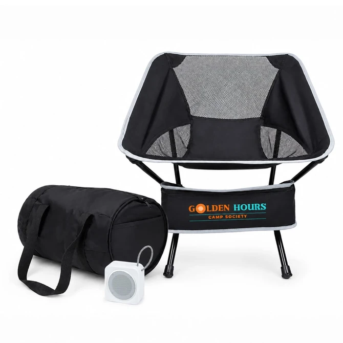 A portable black camping chair with a mesh back, accompanied by a black storage bag and a small speaker.