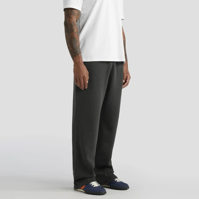 Faded cuffless track pants in dark grey, worn with a white t-shirt and shoes. Features branding.