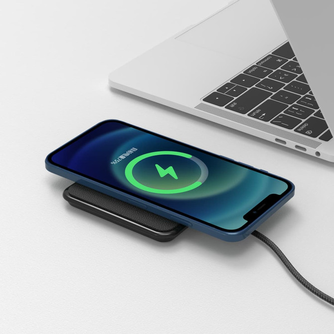 A black eco-friendly wireless charger is placed on a white surface, with a phone displaying a charging icon.