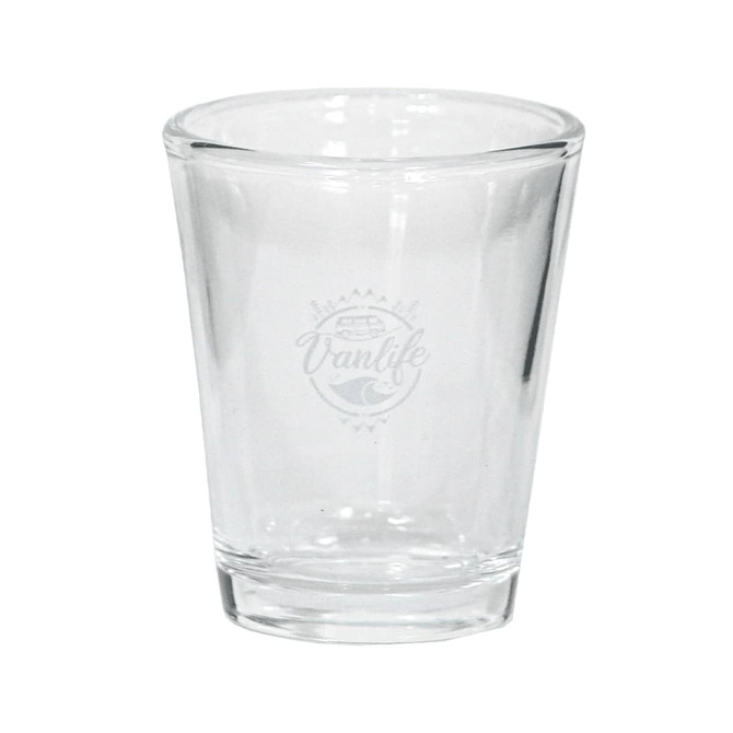A clear glass shot glass with a logo design on one side.