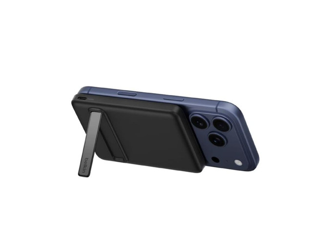 A black magnetic power bank attached to a blue smartphone, featuring a stand on the back. It has branding visible.