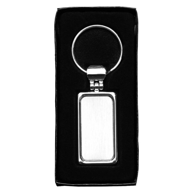 A silver metal keyring with a rectangular pendant, packaged in a black box.