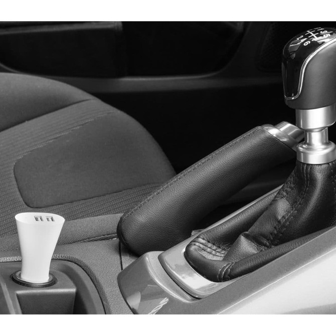 A dual car charger with a sleek design and a black finish, positioned beside a car gear shift in a modern interior.