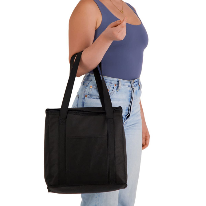 A black cooler bag with sturdy handles, held by a person wearing a blue top and light jeans.