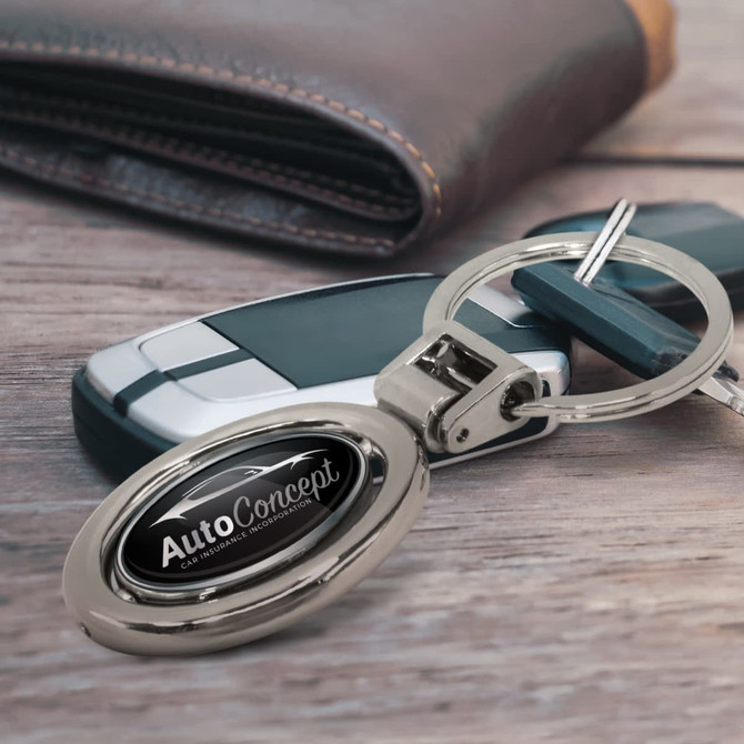 A silver spinning metal key ring displayed alongside a car key and a brown wallet. The key ring has a logo.