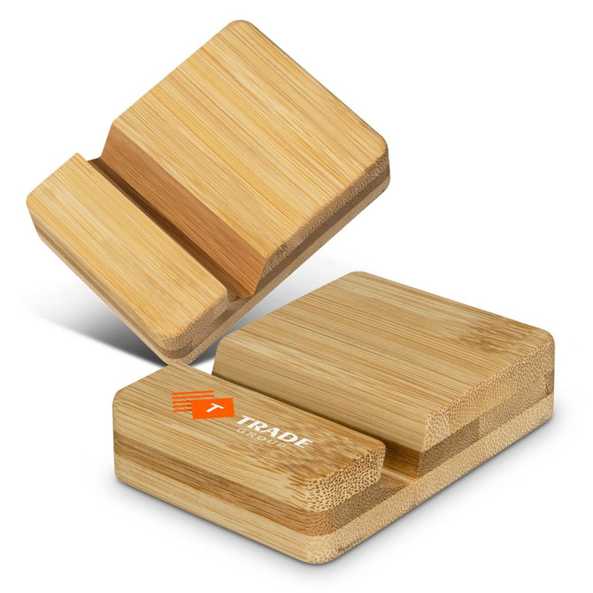 A bamboo phone stand in natural wood tone with a logo, featuring two angled slots for phone support. A bamboo phone stand in natural wood tone with a logo, featuring two angled slots for phone support.