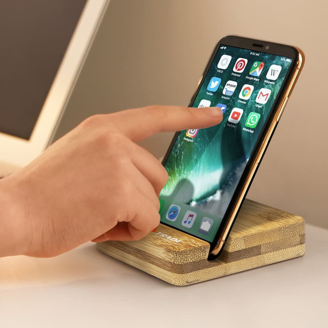 A bamboo phone stand with a phone displaying various apps, featuring a textured base and a sleek design. A bamboo phone stand with a phone displaying various apps, featuring a textured base and a sleek design.