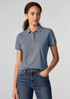 A women's short sleeve polo in light blue, featuring a collar and a logo, paired with jeans.
