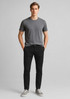 Mens tapered stretch chino pants in black, paired with a grey t-shirt and grey shoes. Features a logo branding.