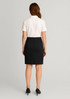 A black women's mid waist stretch chino skirt displayed on a model from the back, paired with a white polo shirt. A black women's mid waist stretch chino skirt displayed on a model from the back, paired with a white polo shirt.