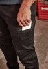 A close-up of a person wearing black stretch jeans, with a hand reaching into a side pocket holding a white item.