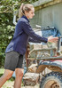 A woman in a navy long sleeve button-up shirt and grey shorts handling buckets outdoors near a vehicle.