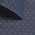 A close-up of a dark chambray fabric featuring a subtle pattern of small, light-coloured dots.
