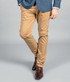 A pair of beige chino pants, featuring a slim fit, worn with a blue blazer and brown dress shoes.
