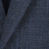 A blazer in a textured navy blue fabric, showcasing a subtle woven pattern. Features a logo on the label.