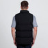 A black puffa vest with a high collar, viewed from the back, worn over a grey t-shirt. Features a logo.