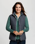A woman wears a grey puffer vest over a green top, featuring a branding logo on the vest.