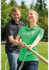 A green ladies polo shirt and a black men's polo shirt displayed on models outdoors, with trees in the background.
