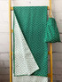 A green rPET beach towel with a cloud pattern, hanging next to a matching drawstring pouch.