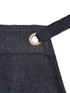 A dark denim bib apron featuring a metal grommet for adjustable ties. It includes a branding logo. A dark denim bib apron featuring a metal grommet for adjustable ties. It includes a branding logo.
