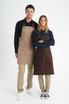 A beige and brown bib apron is displayed on two models against a white background, showcasing a logo on the product.