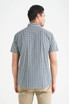 A man wearing a short sleeve button-up shirt with a checkered pattern in navy and white, viewed from the back.