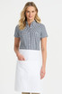 A short sleeve button-up shirt in black and white gingham pattern, paired with a white apron. The model is smiling.
