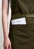 A green apron featuring a front pocket holding a menu card, with a simple logo.