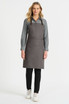 A grey bib apron with leather straps, worn over a grey shirt and black pants, featuring a front pocket.