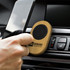 A bamboo car phone holder with a black circular grip, placed in a car dashboard vent, holding a smartphone. A bamboo car phone holder with a black circular grip, placed in a car dashboard vent, holding a smartphone.