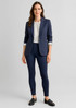 A woman wearing a navy blazer and high-rise navy leggings, styled with a white blouse and loafers.