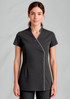 A short-sleeved women's crossover tunic in dark grey with white piping and a button detail, featuring a logo.