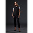 A black softshell vest is worn by a woman styled with sleek trousers and heels against a dark background. It features a logo.