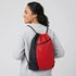 A drawstring backpack in red and black, featuring a zipper pocket and worn on a person’s back.
