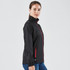 A black women's rain jacket with red accents, featuring a zippered front and side pockets, and a logo on the fabric.