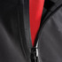 A close-up of a black softshell jacket featuring a red interior and a zippered front. The jacket has a logo.