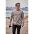A man wearing a beige crew neck fleece sweater and sunglasses, holding a camera while walking on a pier.