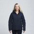 A woman wearing a navy soft shell jacket with a hood and zippered pockets, featuring a logo on the sleeve.