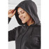 A woman in a dark grey fleece hoodie with a full zip and hood, smiling and looking down.