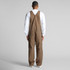 Canvas overalls in brown, featuring a simple design and a logo, viewed from the back on a model.