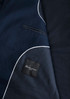 A navy blue men's jacket with white piping and a pocket design, featuring a branded label inside.